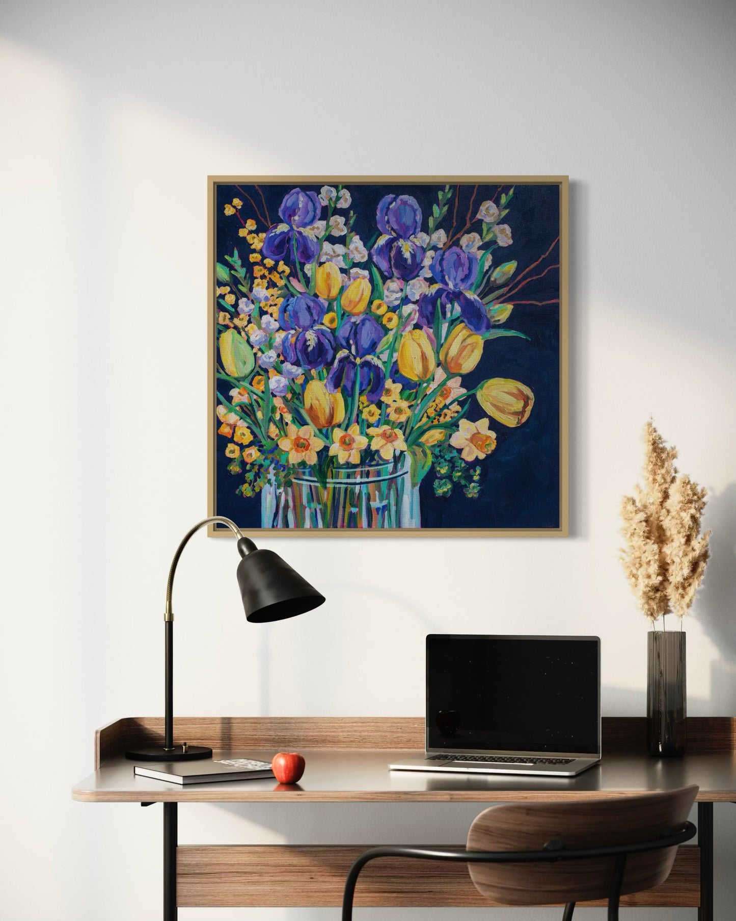 home office setting with simple desk and chair and a cheerful spring floral still life painting on the wall.