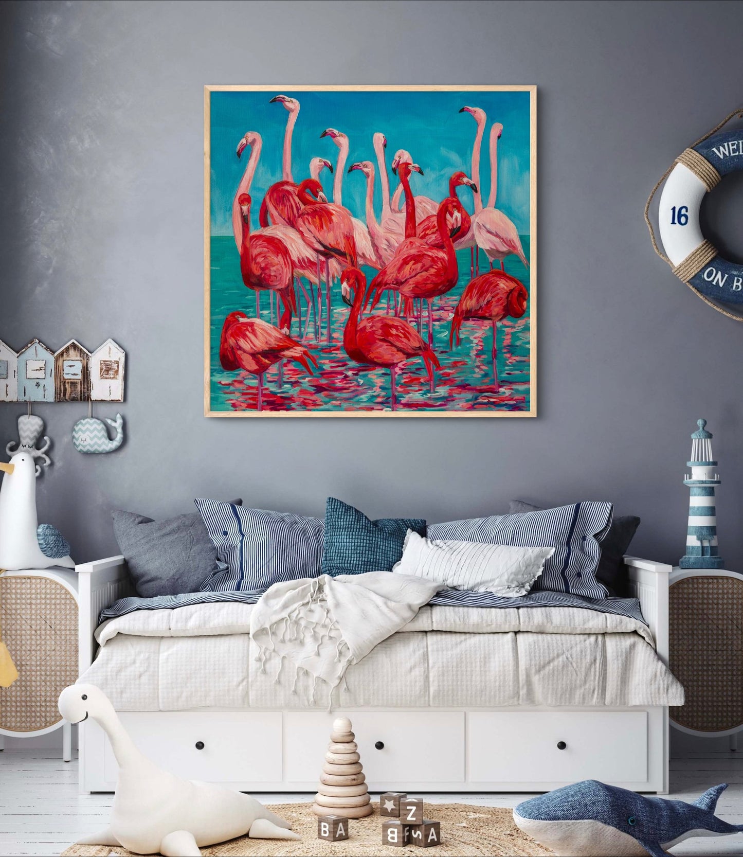 Childrens room with bed and decor having navy and cream sea themed decor including a bright and cheerful painting of flamingos.