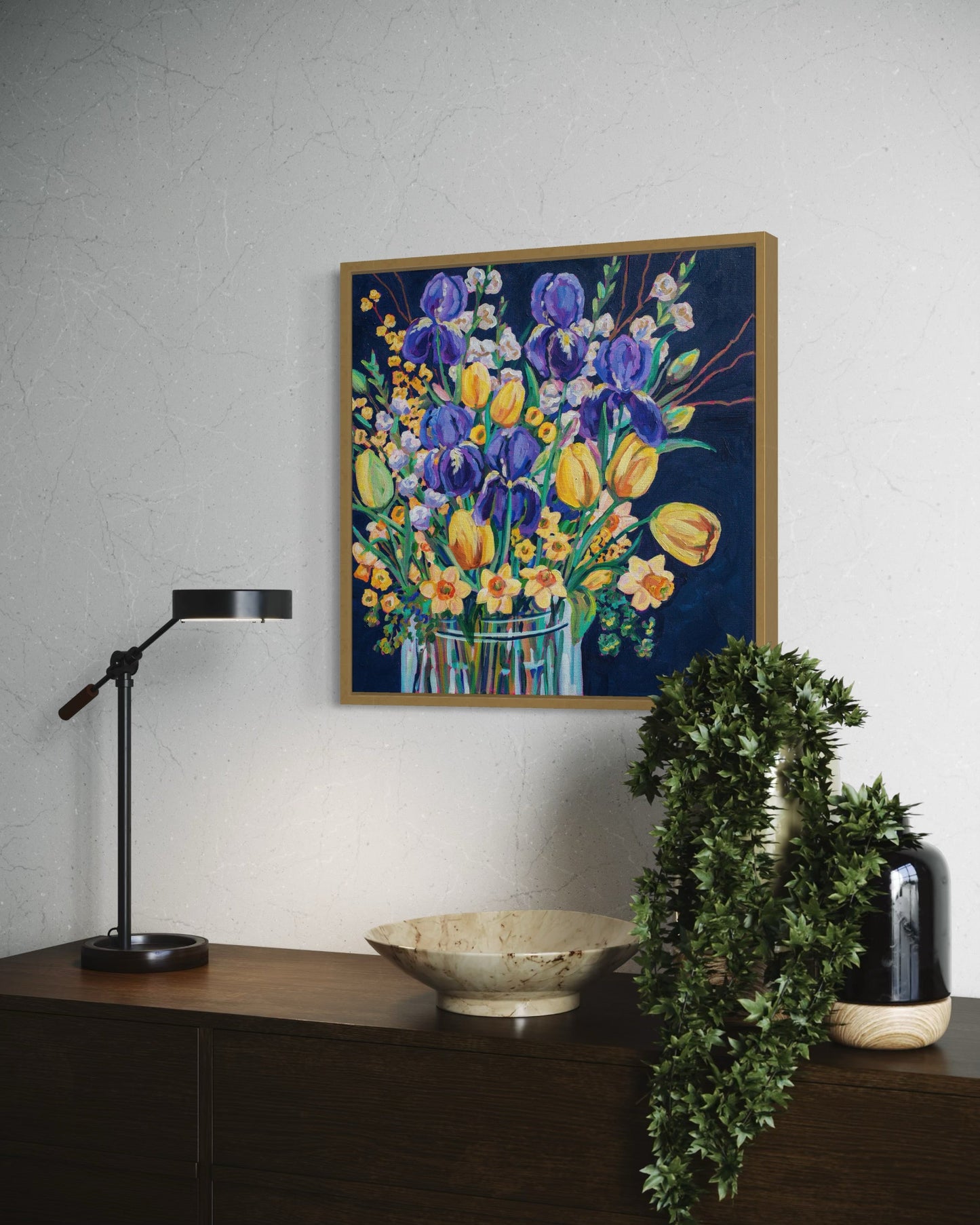 Bright spring floral still life painting above a credenza with plant, vases and lamp.