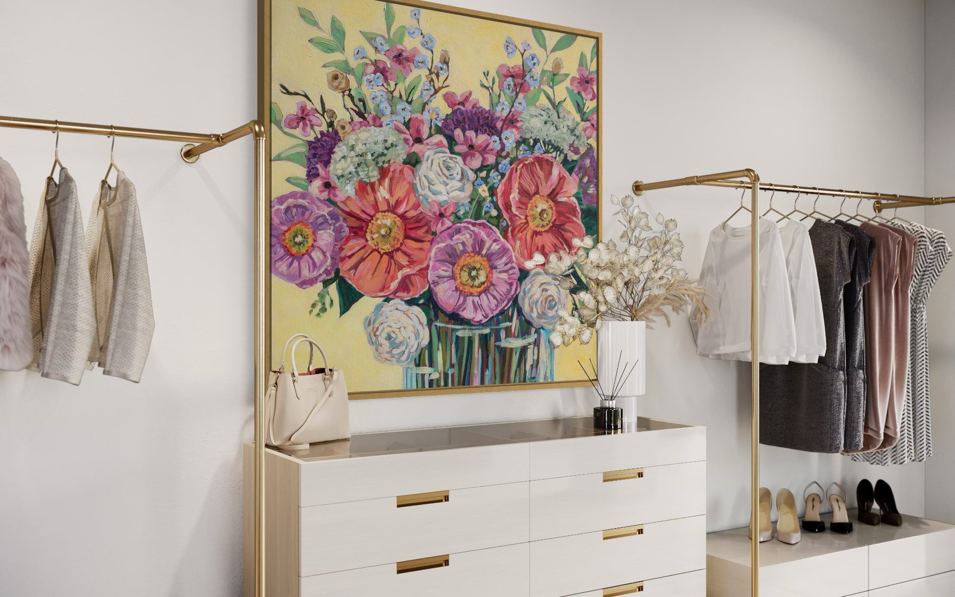 Modern bedroom with white dresser, floral artwork, and clothing on gold racks.