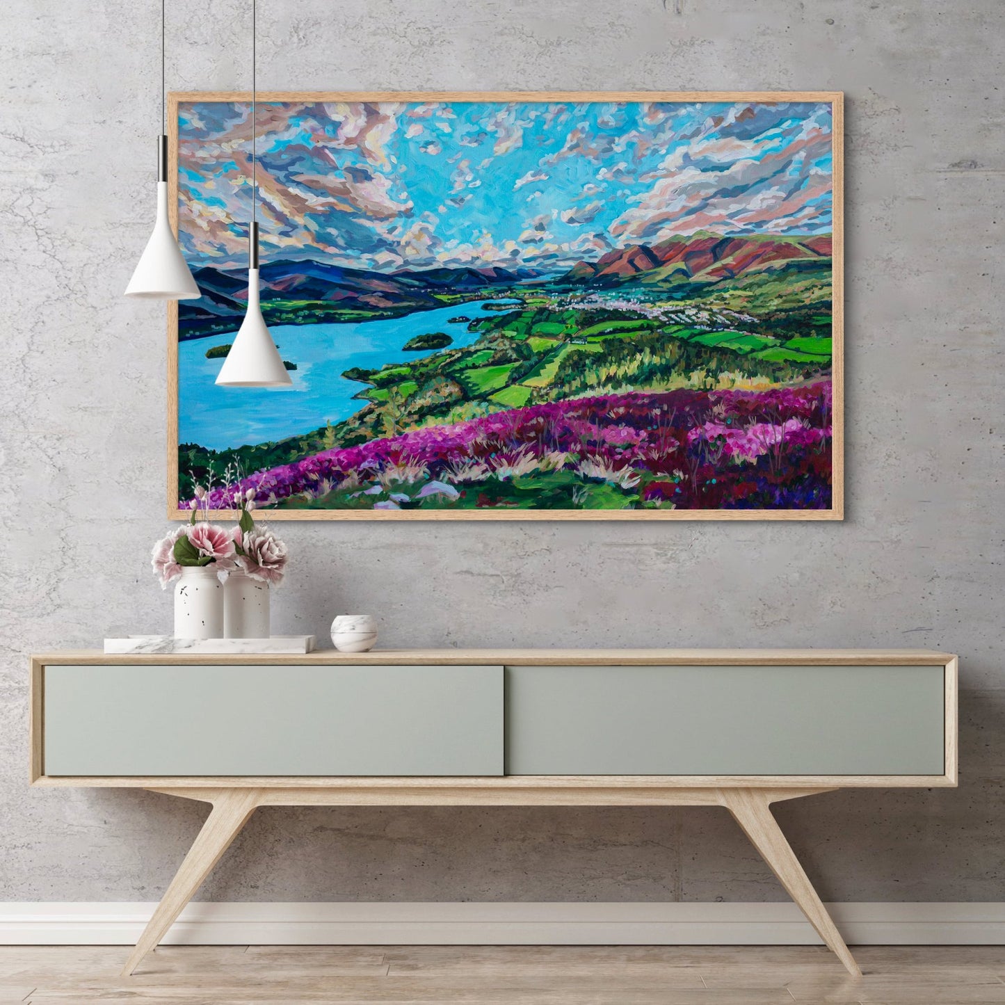 modern credenza with vases holding flowers, and hanging lamps, large statement piece striking landscape of a British Countryside lake district hangs on wall