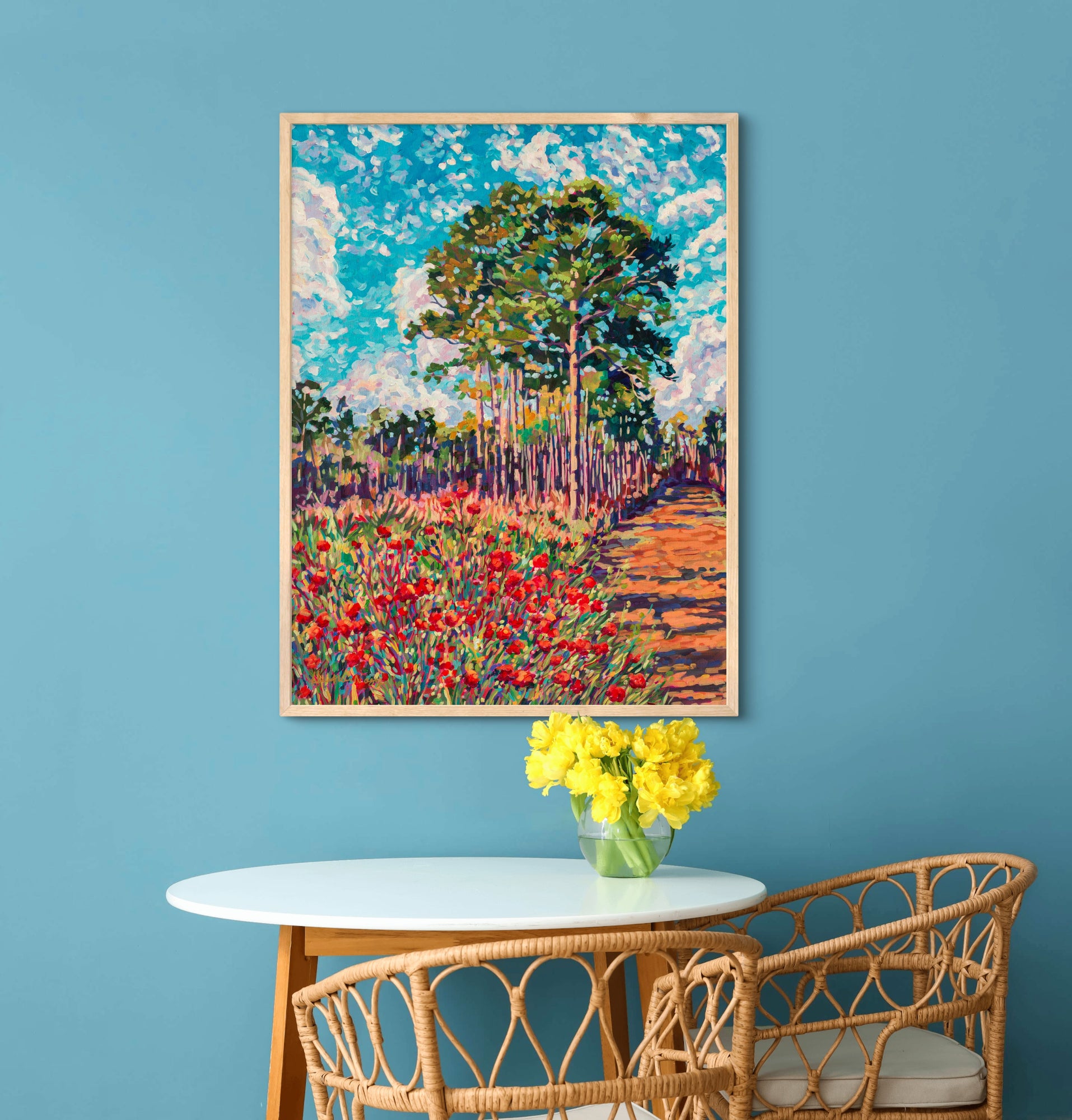 small kitchen nook table with flowers with blue wall and vibrant landscape painting by artist Heather Nagy
