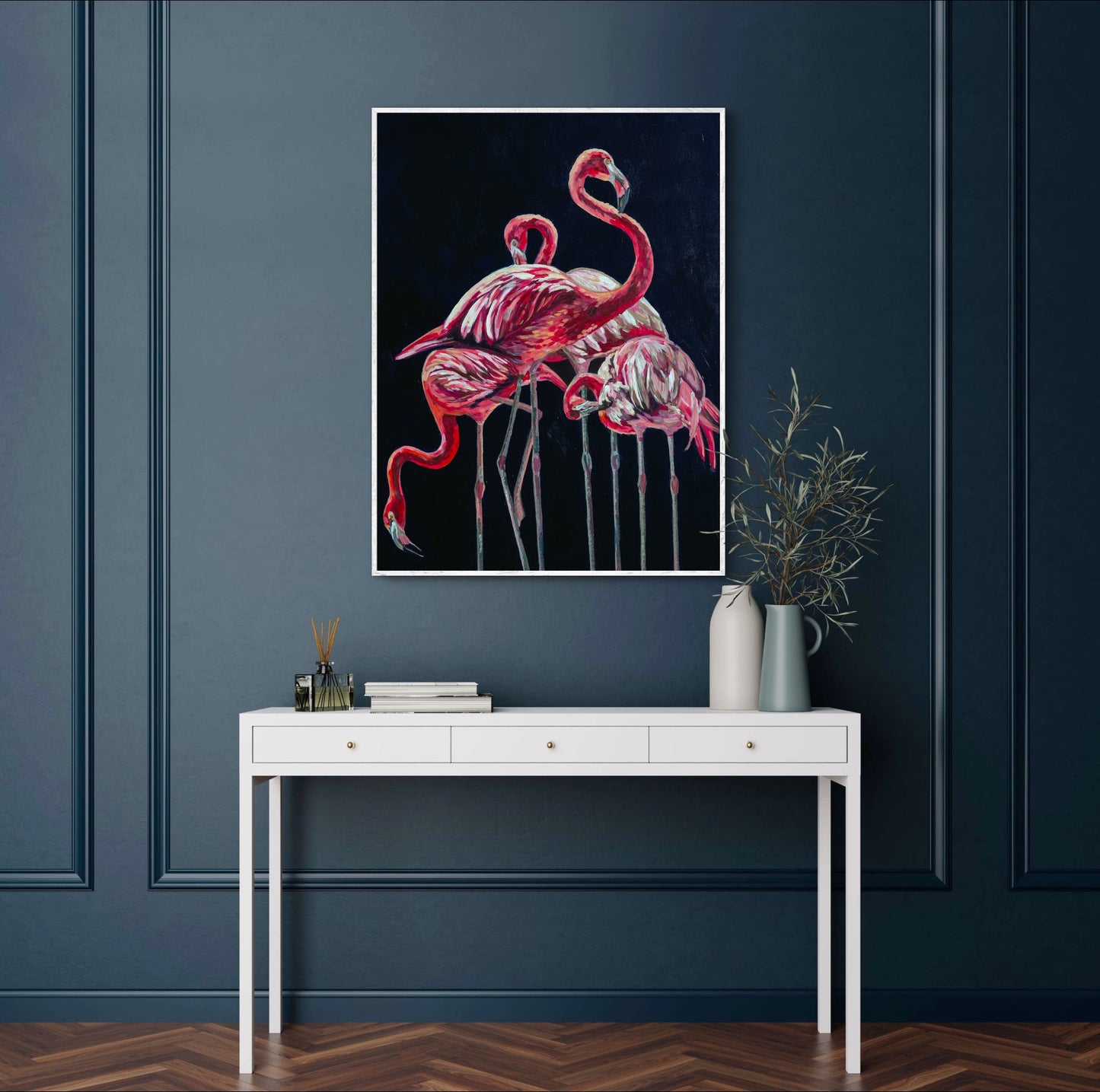 Navy room with wood floors and white side table against wall with vases, above hangs painting of dramatic flamingos that glow against their navy background.