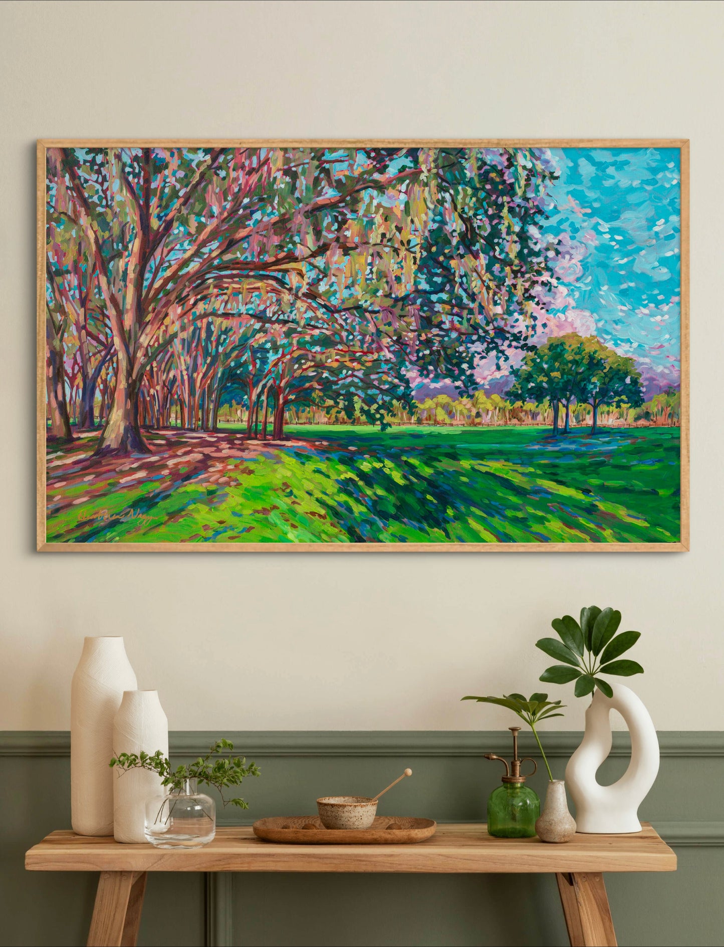 Tree and park natural impressionist landscape acrylic painting on wall above side table with vases and plants.