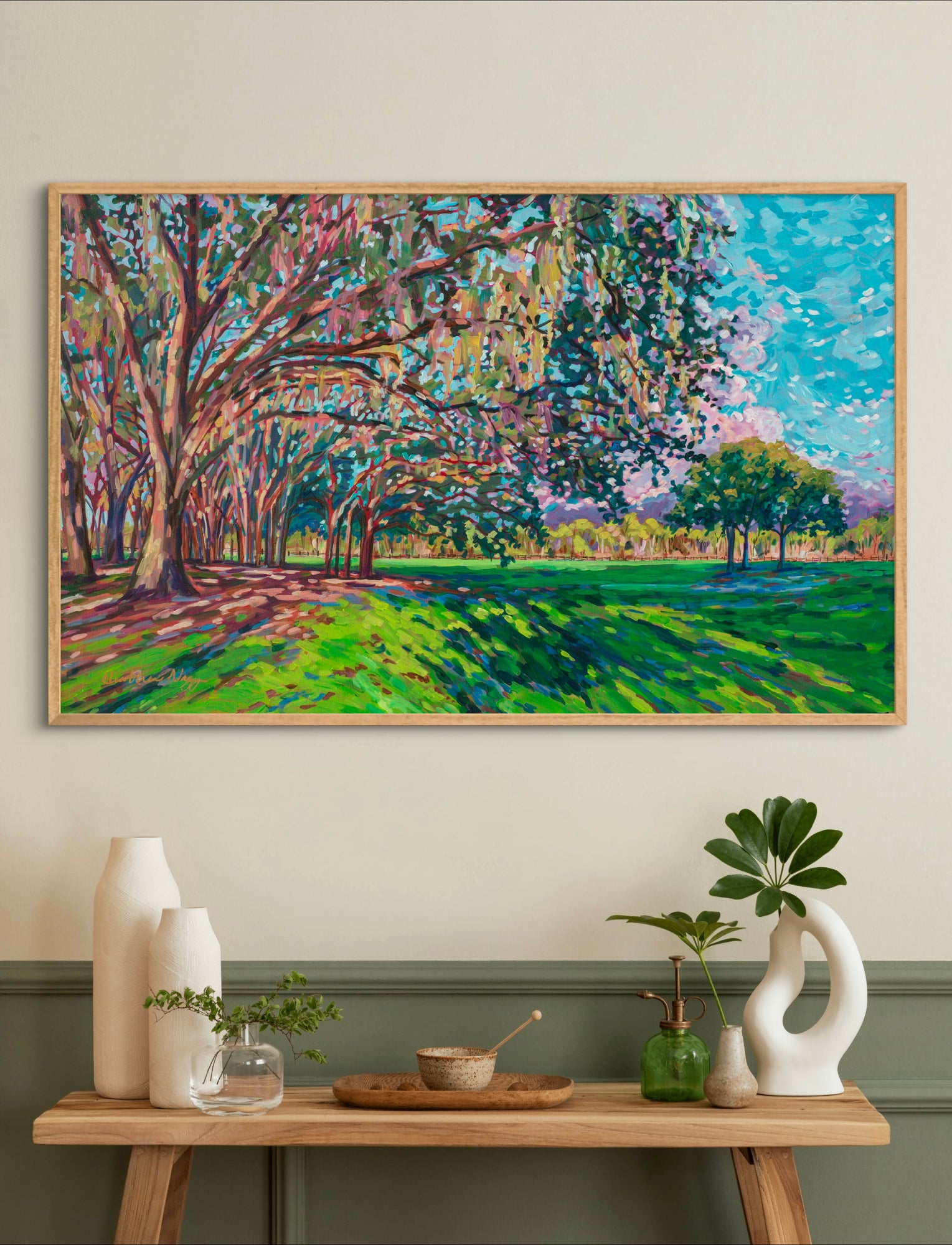 Tree and park natural impressionist landscape acrylic painting on wall above side table with vases and plants.
