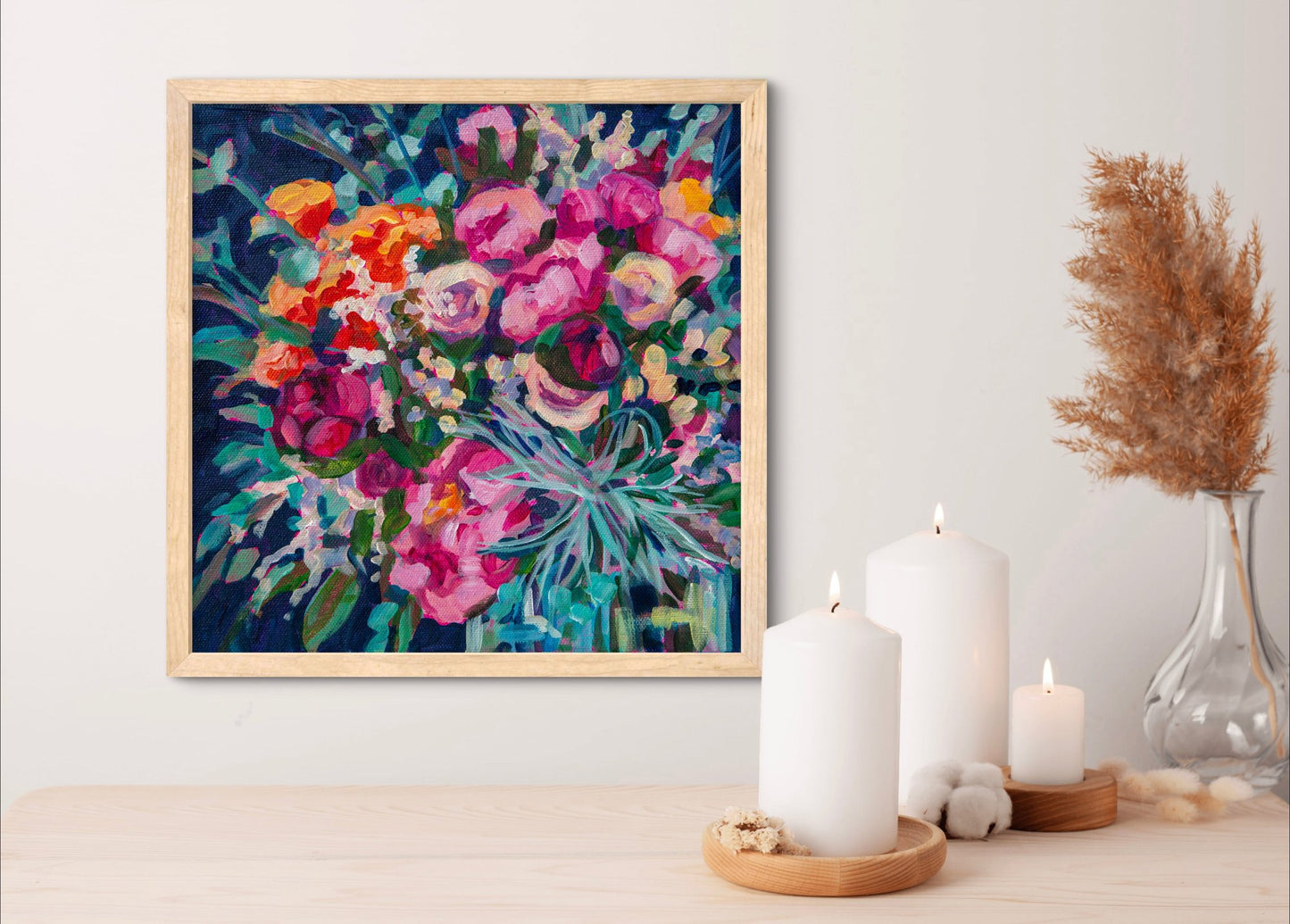 small square flower painting still life on wall above wood shelf with candles and vase in neutral light wood colors.