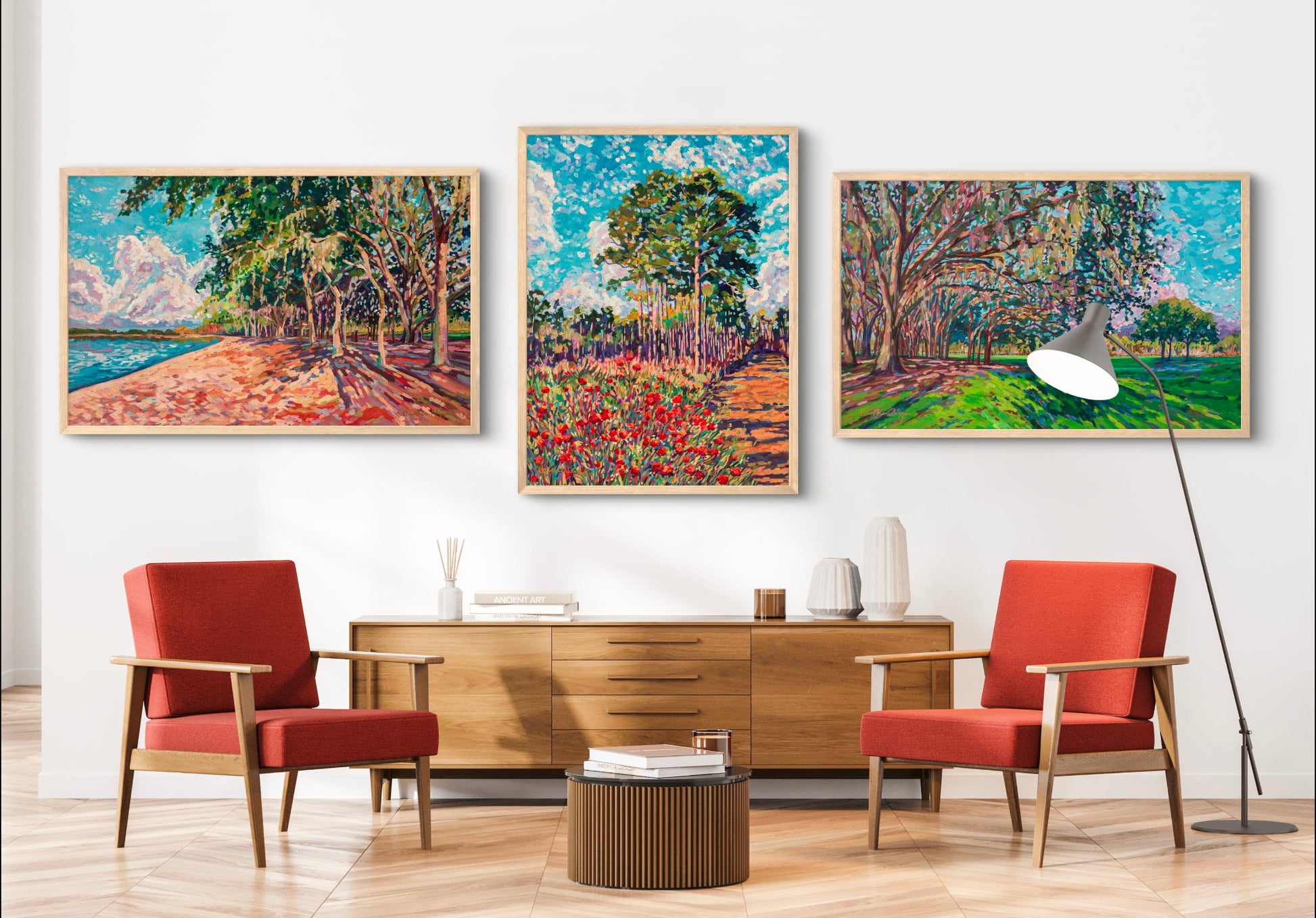 Modern sitting room with two orange chairs and a credenza with three dramatic paintings, impressionist landscapes of park setting in Florida.