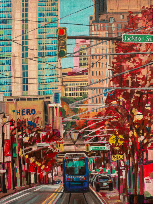 An acrylic painting depicting a vibrant street scene of Atlanta with a streetcar, autumn trees, and modern buildings under a clear sky.