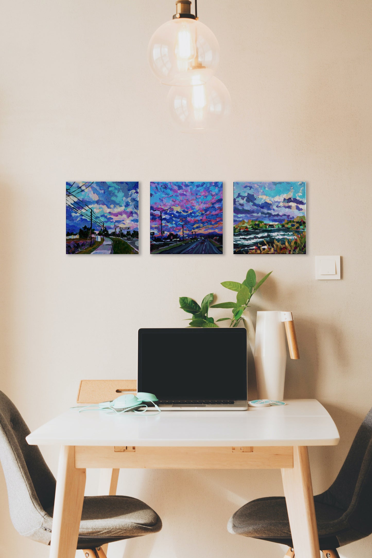 three small vibrant impressionist paintings at table with comptuer