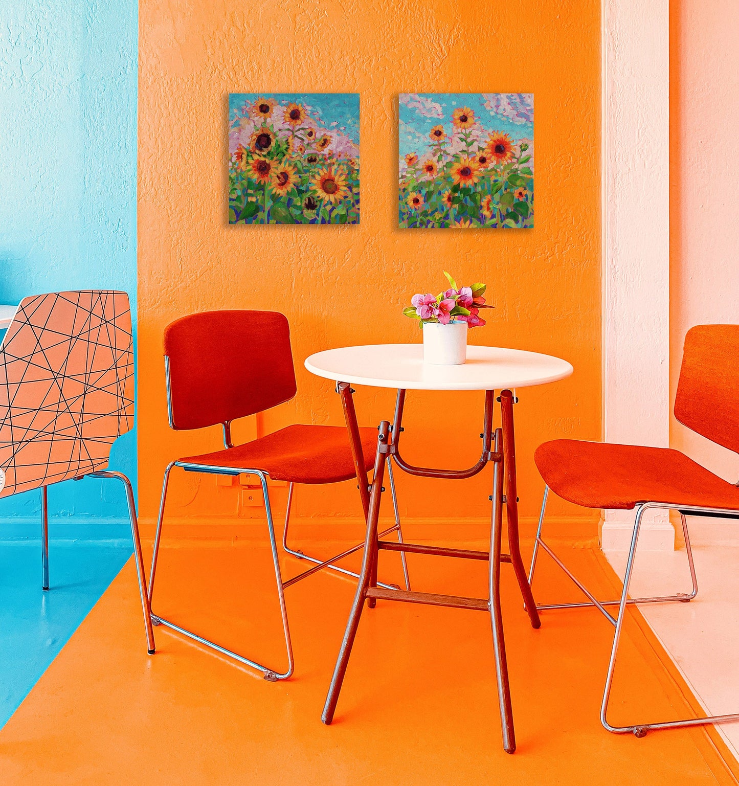 two sunflower paintings in a orange room with table and chairs