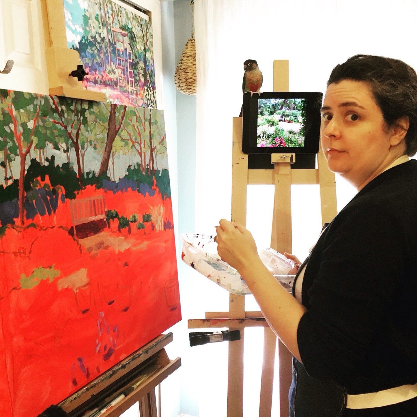artist in studio with painting in progress and pet bird