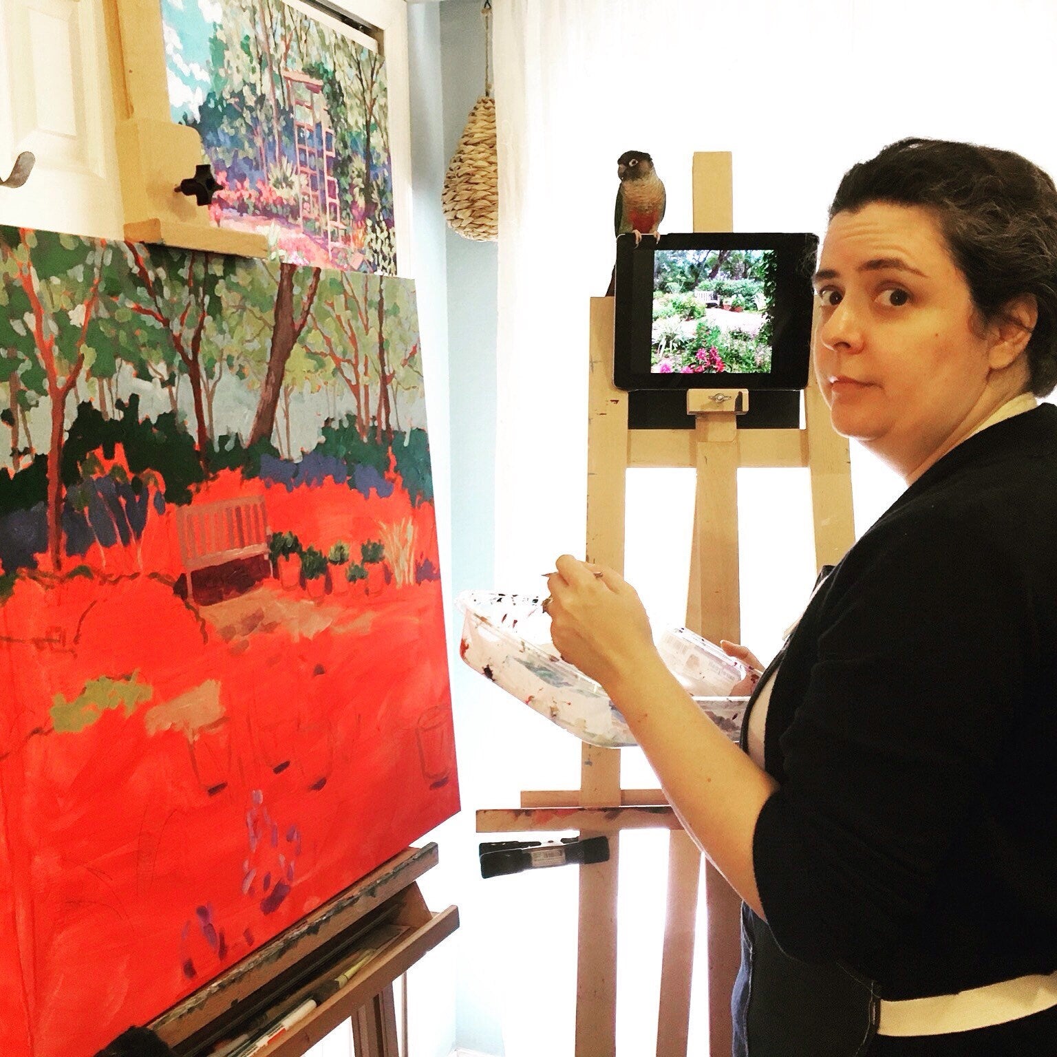 artist in studio with painting in progress and pet bird