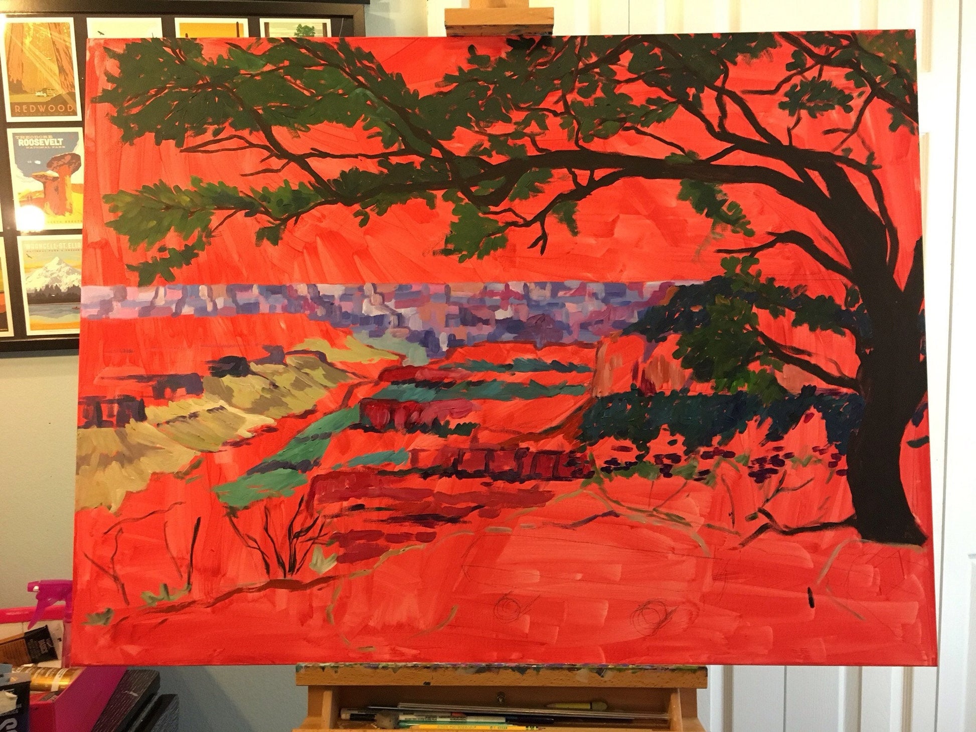 painting in progress on easel on top of bright cadmium red wash