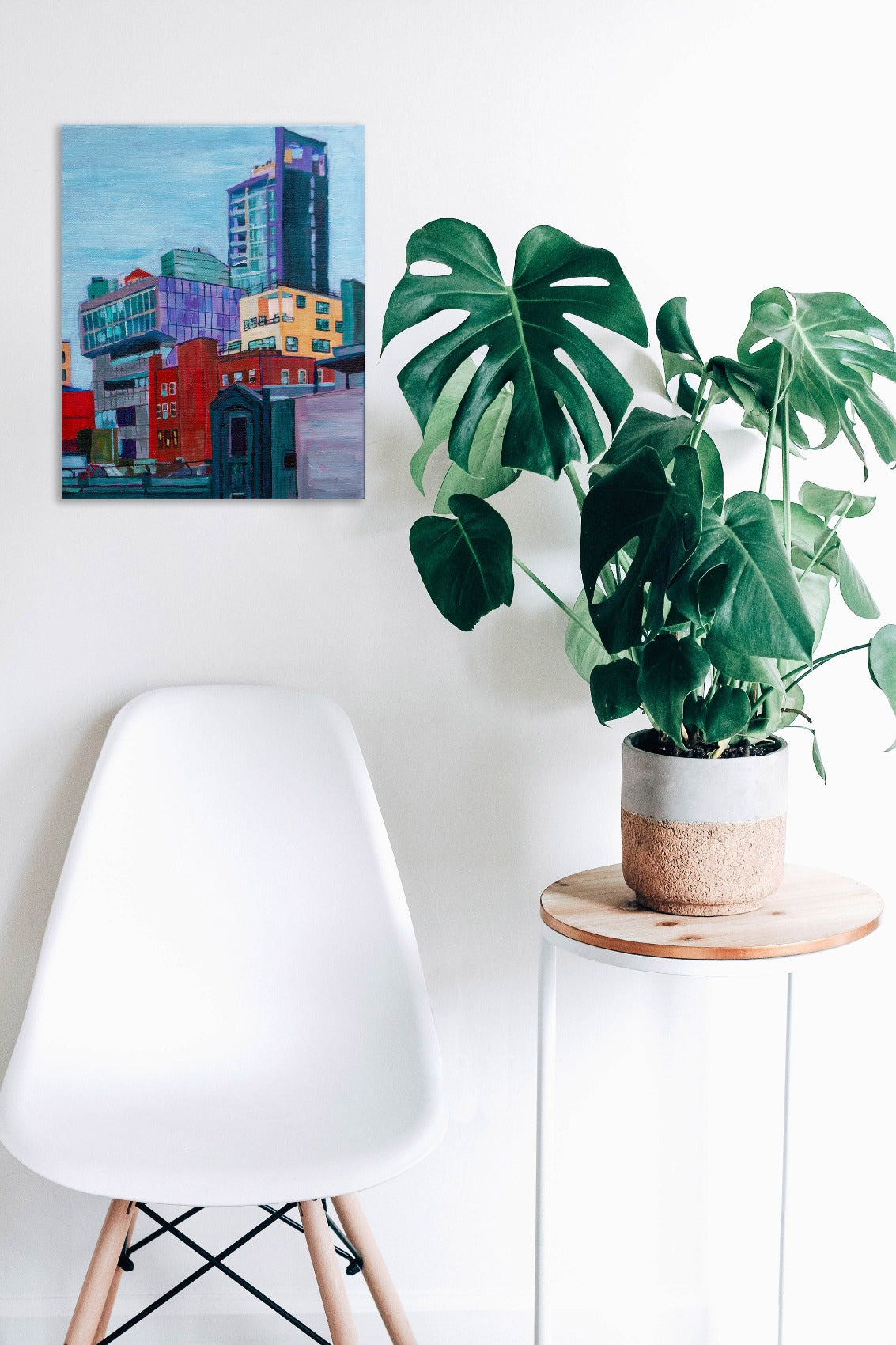 NYC buildings painting on wall with plant and chair