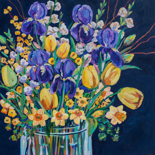 Colorful bouquet of flowers including tulips and irises in a clear vase on a dark background