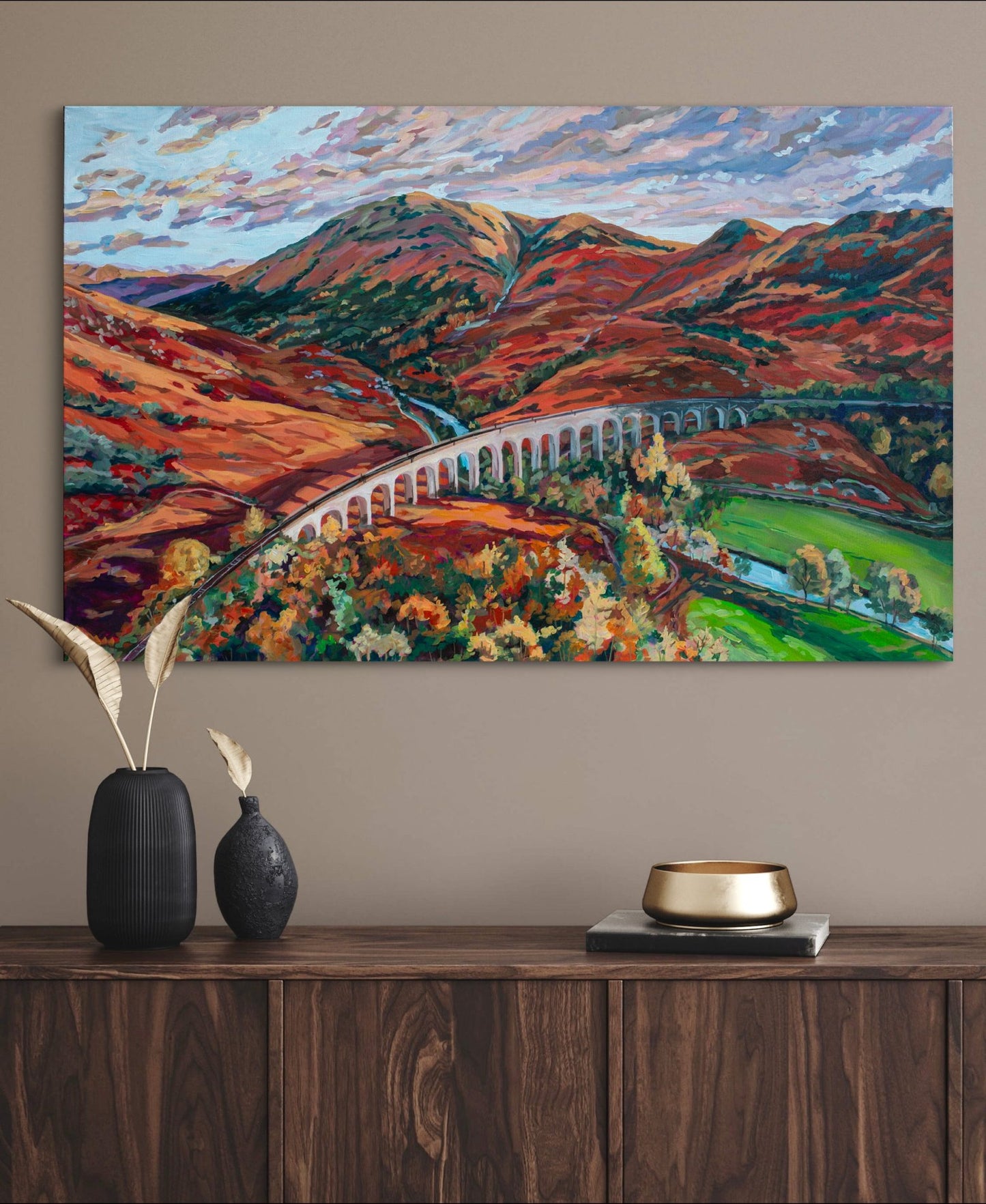 Ft William area of Highlands of Scotland Autumnal painting over ark brown wood credenza with decor.