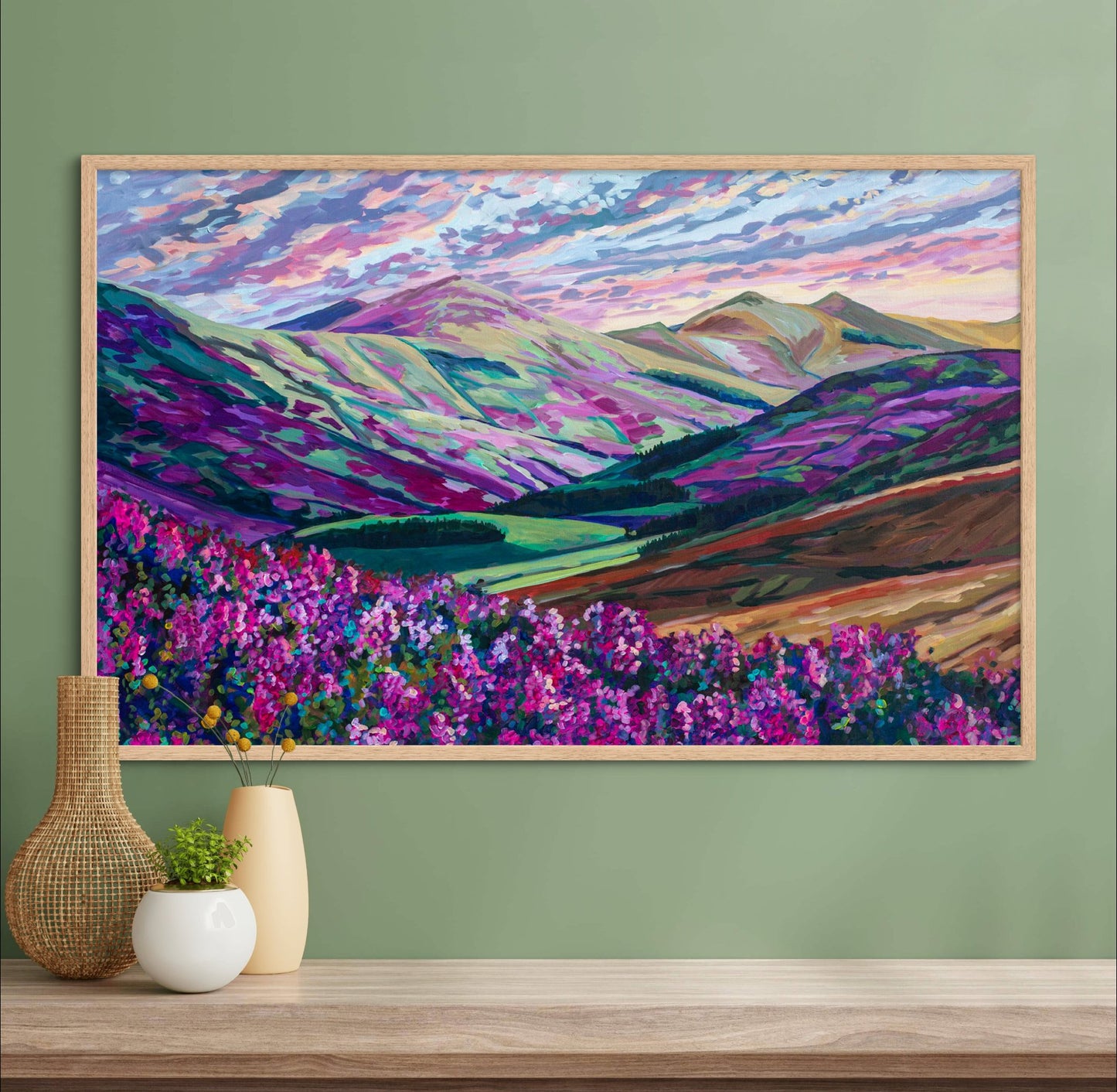 Rugged landscape painting of mountains, rolling hills, Heather, dramatic lighting on green wall over shelf with vases.