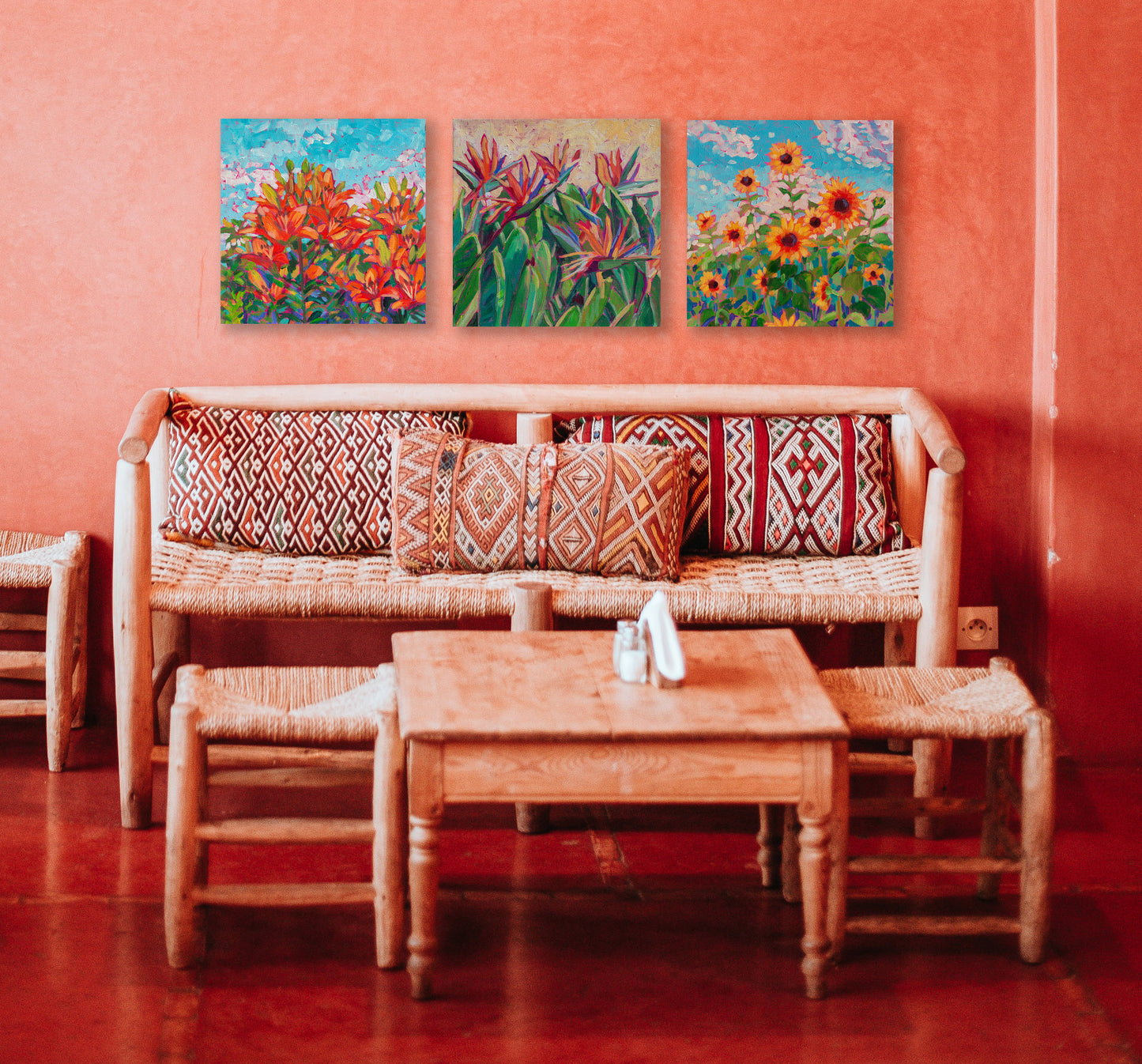 three floral paintings of orange flowers in an orange Southwest themed room