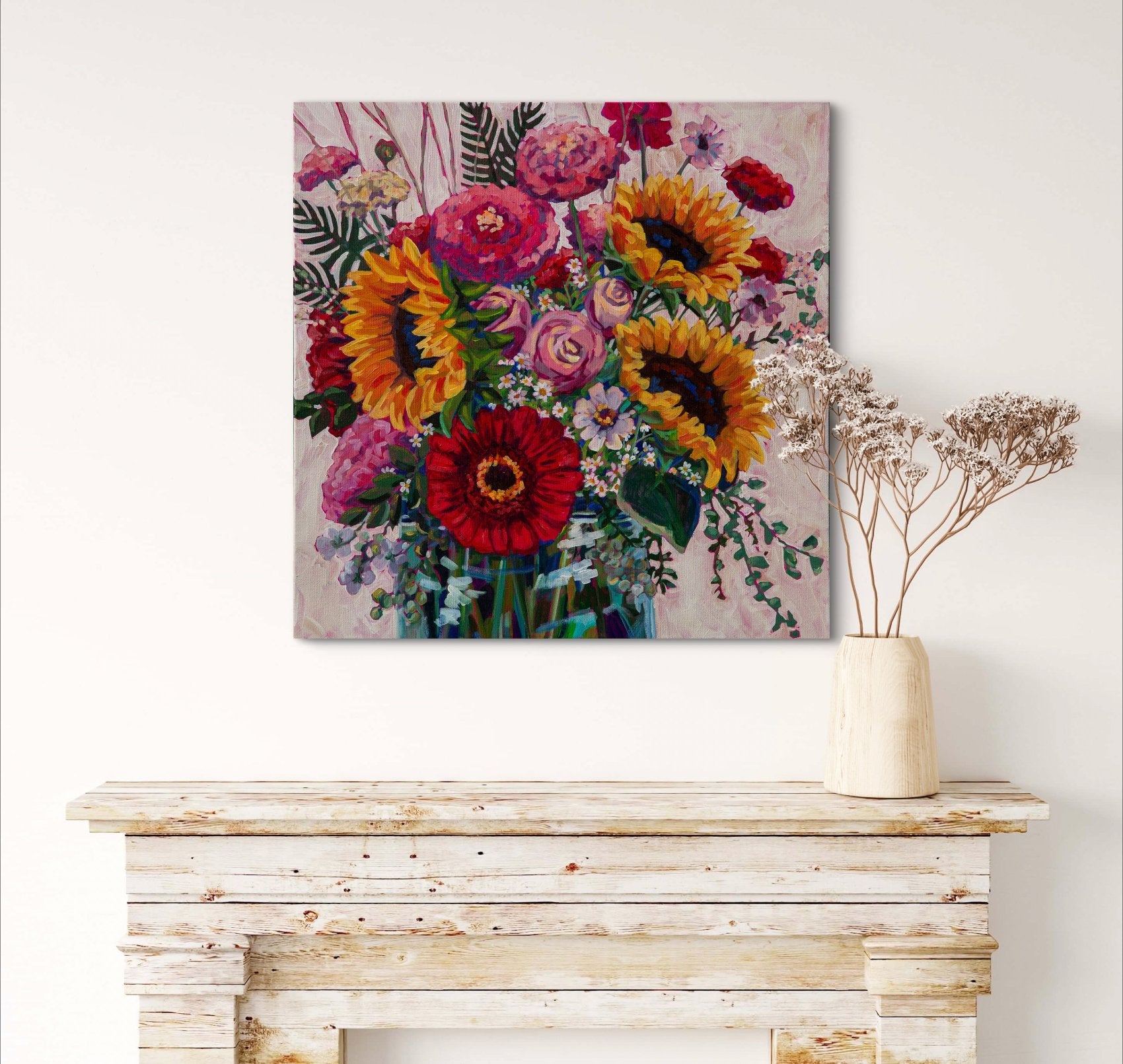 Vibrant floral still life with sunflowers, dahlias and zinnias cheerful expressive painting on wall above light wood mantle with vase and dried flowers.