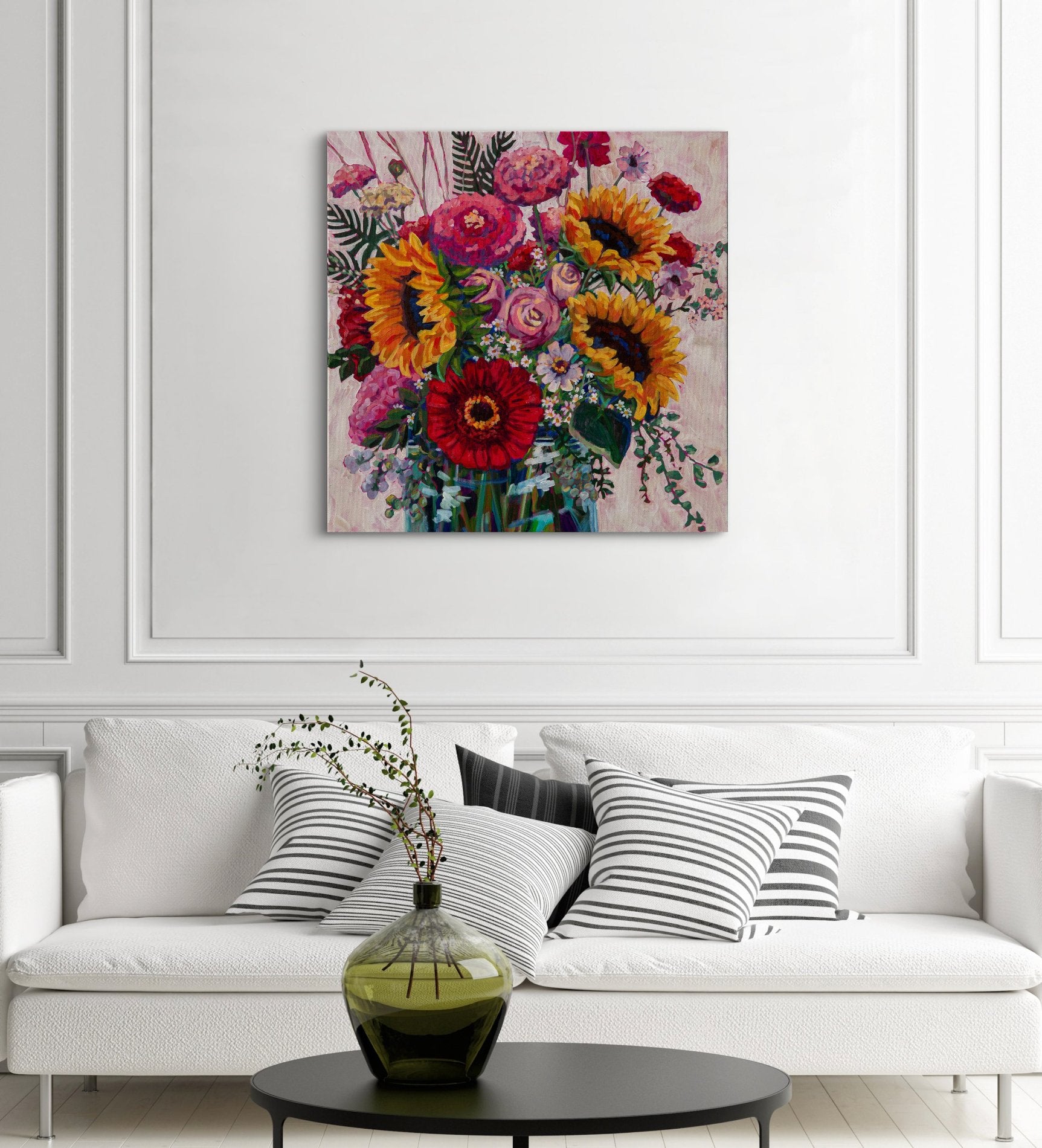 modern decorated living room with sleek white couch and striped black and white pillows with a black coffee table and vase, large bright statement piece of modern floral arrangement still life painting.