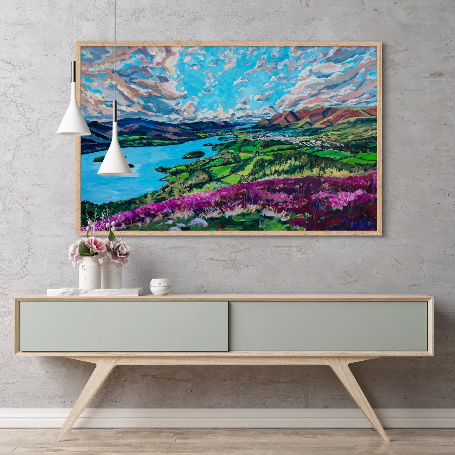 modern credenza with vases holding flowers, and hanging lamps, large statement piece striking landscape of a British Countryside  lake district hangs on wall