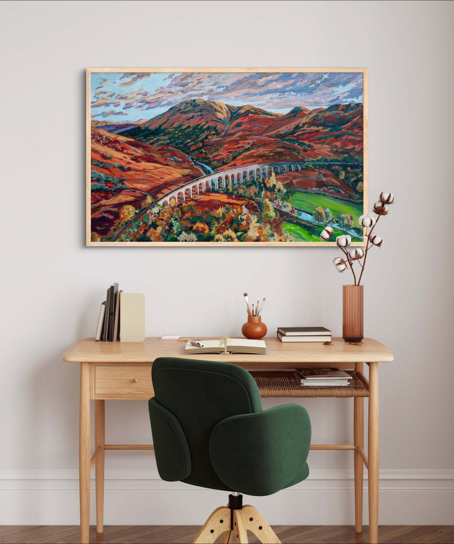 large statement piece landscape painting of highlands of Scotland over a small wood desk with a blue office chair.