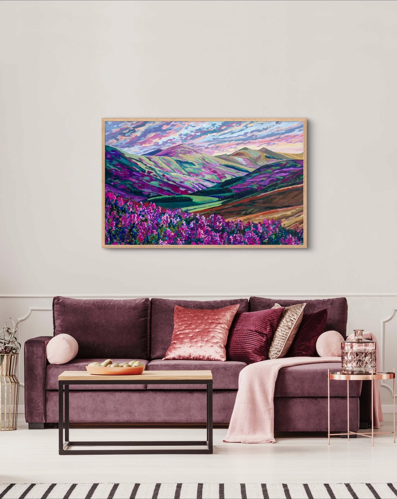 living room with a mauve purple velvet couch and pink accents with dramatic painting showing flowering wild heather in the Scottish countryside on the wall.