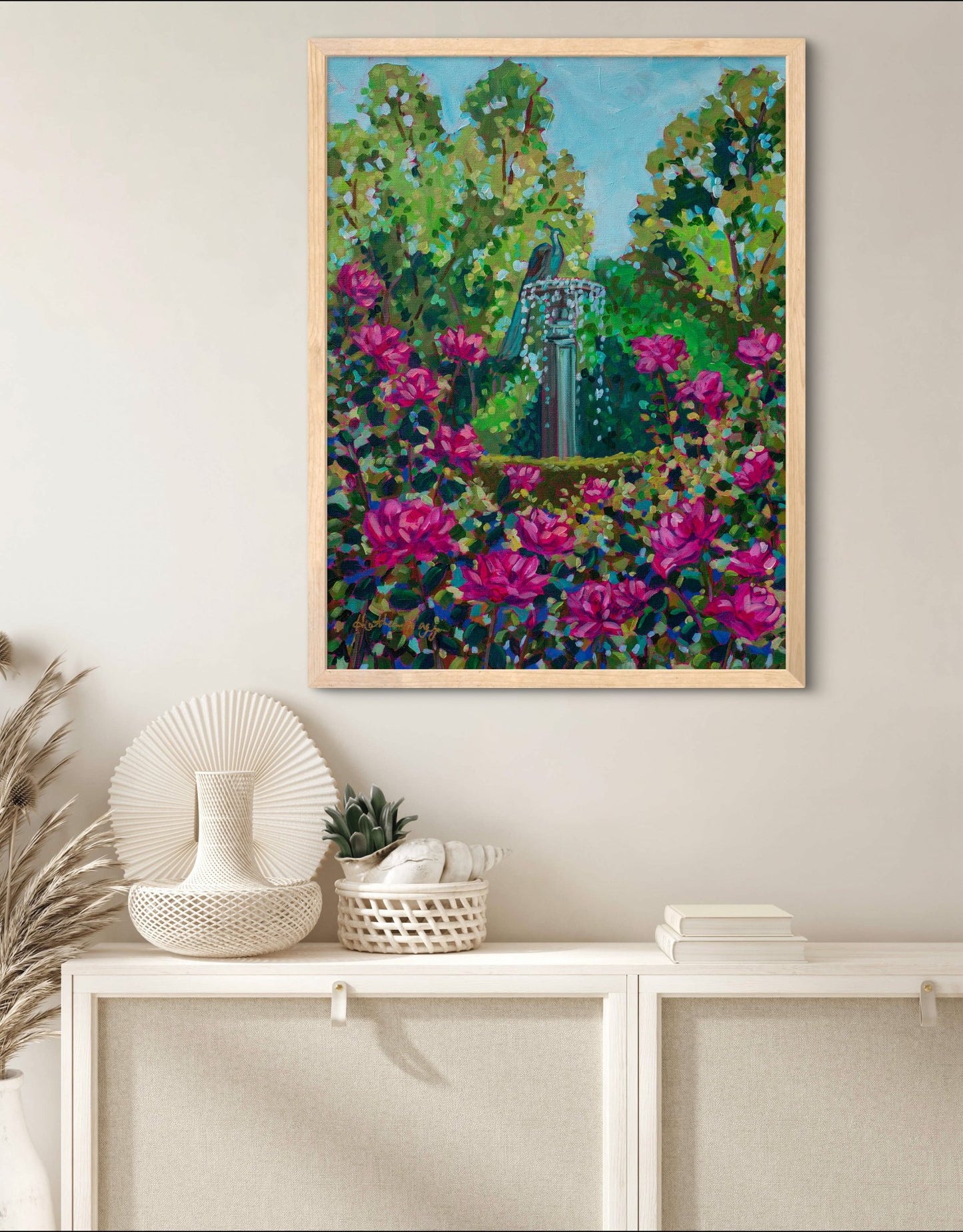 vibrant impressionist garden painting with pink blooms in neutral room above bookshelf.