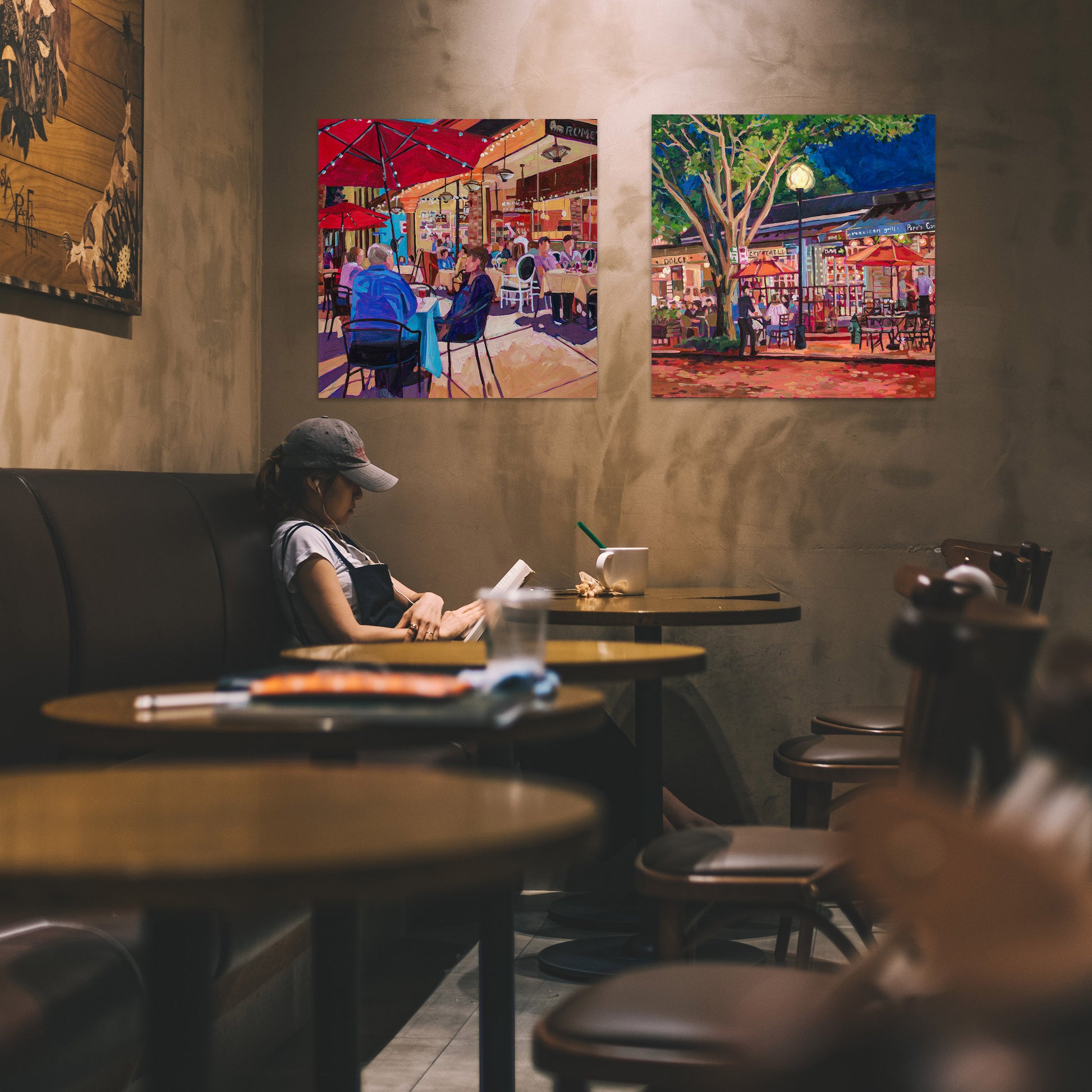 Two Nightlife paintings hung in cafe, Winter Park Nightlife 5 painting 20x20 inches vibrant outdoor cafe scene with dramatic light people seated and umbrellas