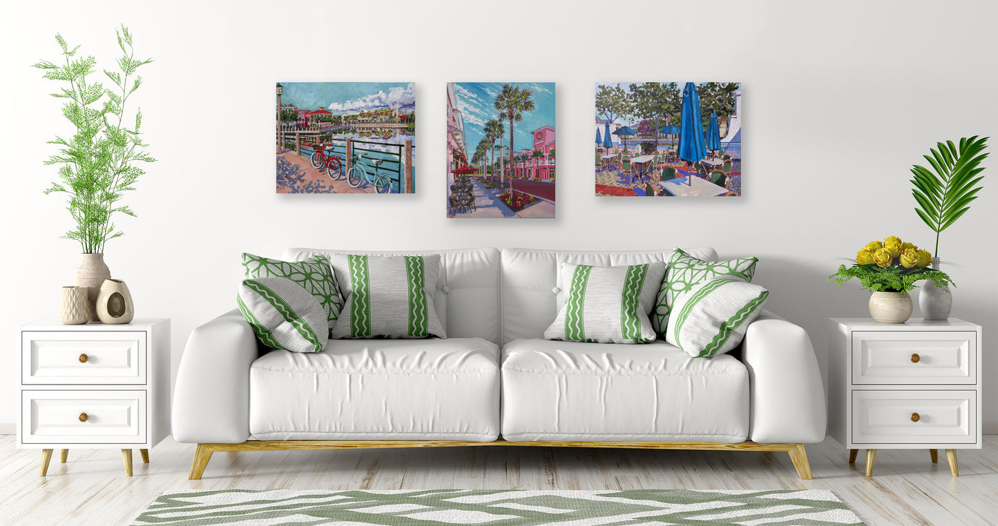 three paintings of celebration Florida's town center in a white and green living room space