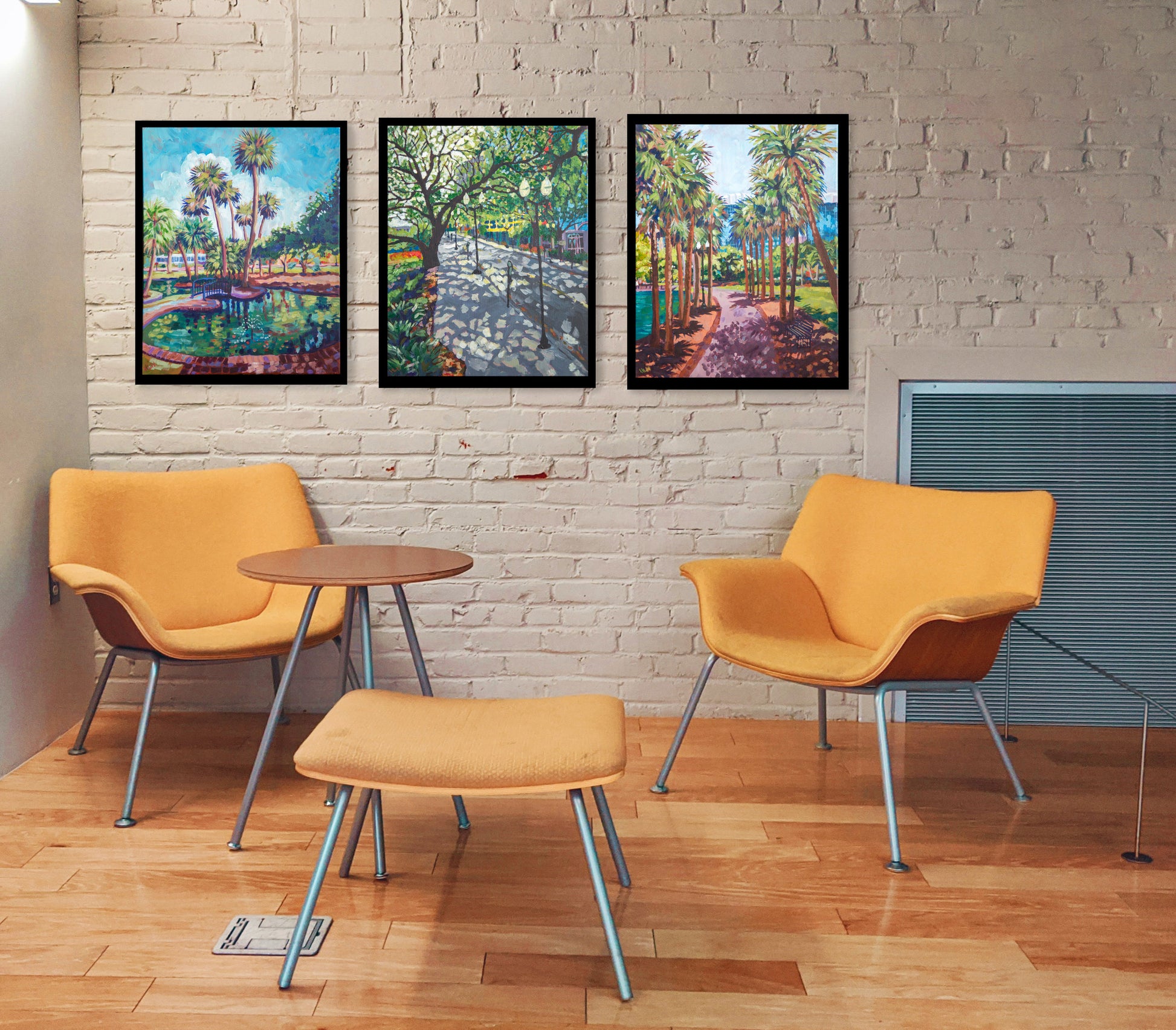 three impressionistic paintings of Lake Eola Park in Orlando Florida on the wall of sitting area with chairs and table