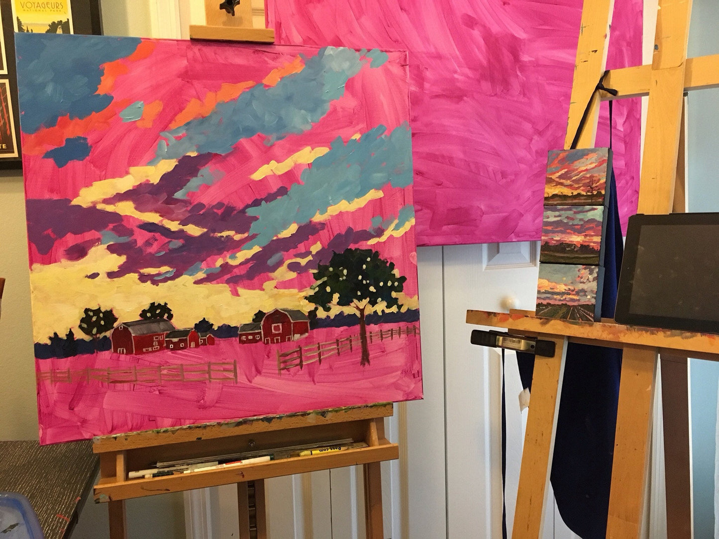 painting in progress in artist studio on easel with three small studies being referenced for the sky