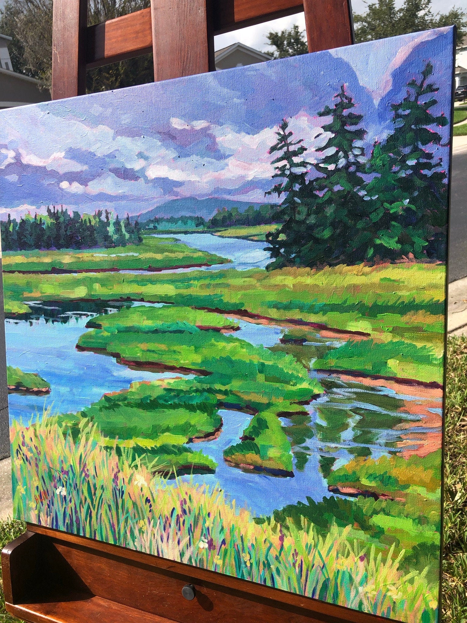 painting on easel outside: 20x20 painterly original painting of Wetlands on Mount Desert Island Maine with dramatic sky and evergreen trees. 