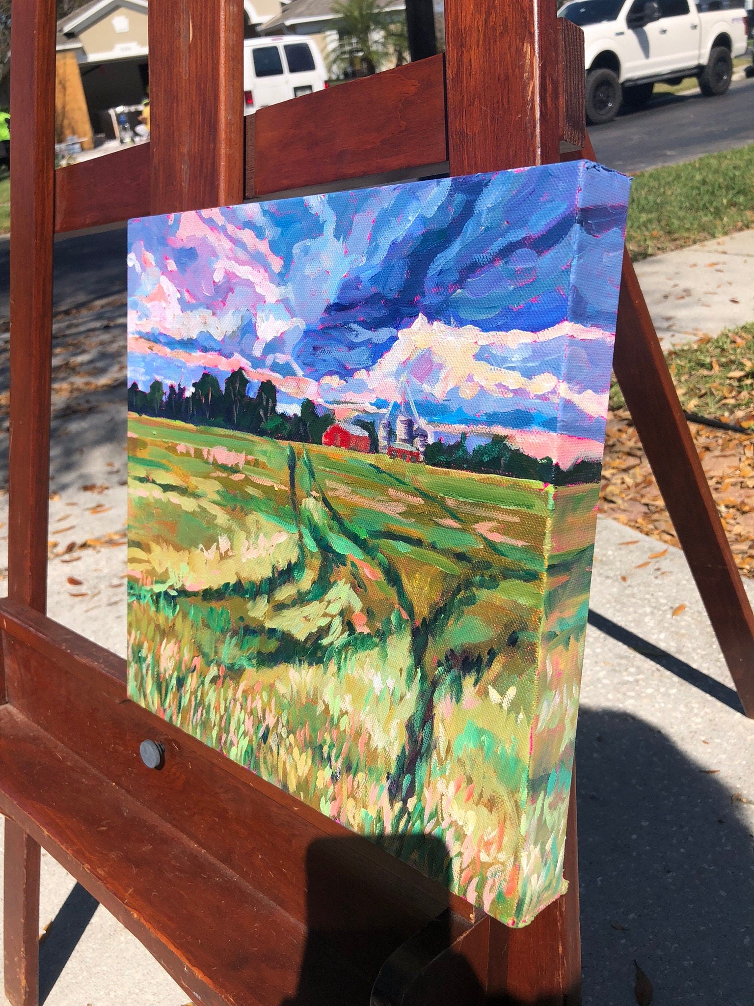 farmland painting with dramatic sky on easel