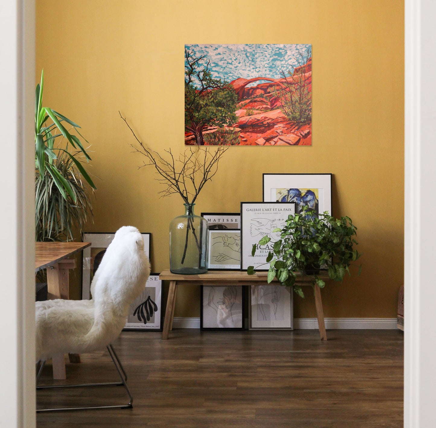 Arches National Park painting in yellow room with bench and desk