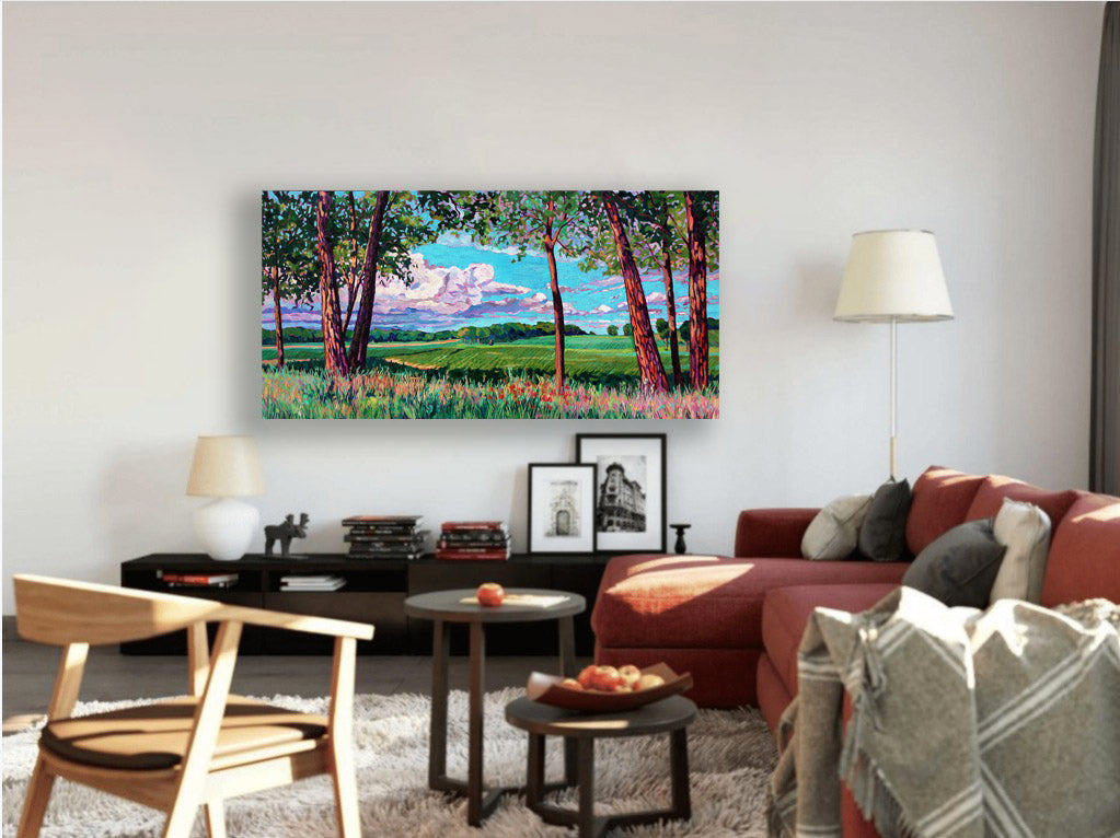 Original vibrant impressionistic painting of Michigan farmland with trees and rolling hills and dramatic sky placed in a comfy living room setting